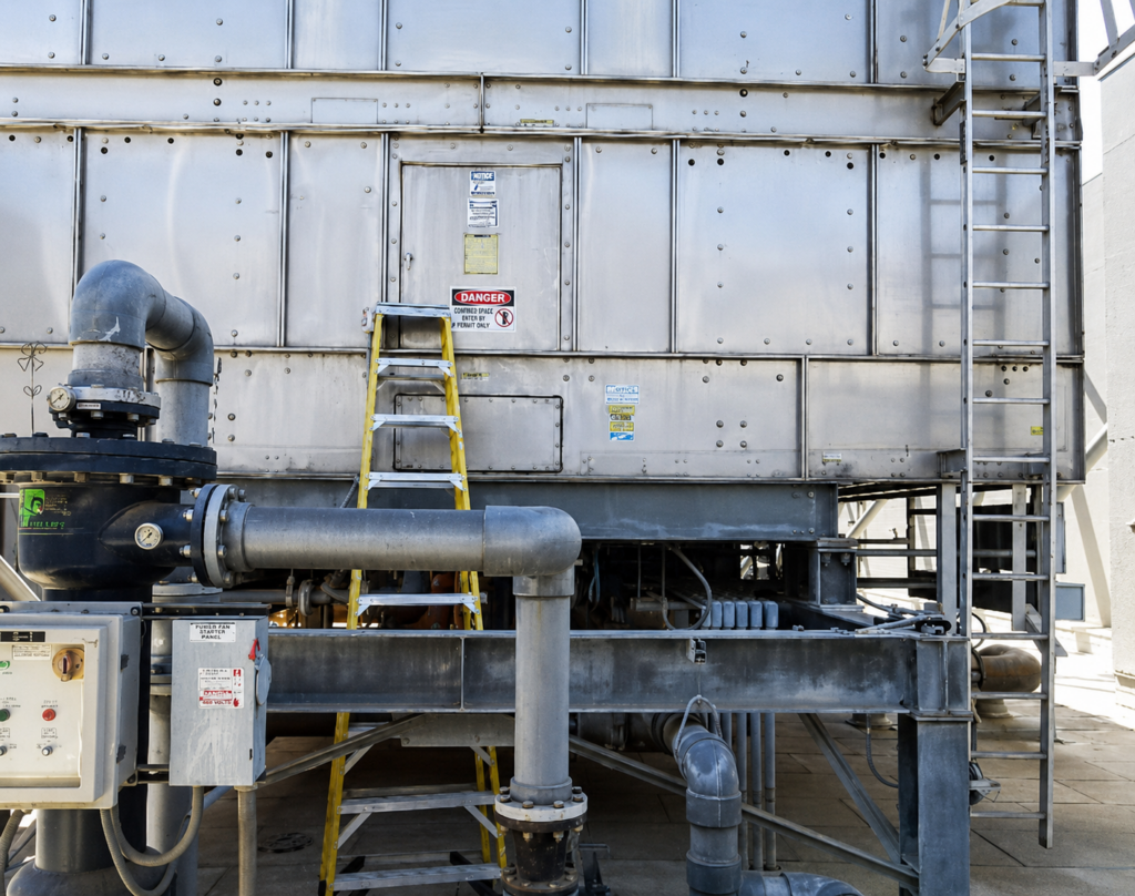 Unsafe ladder access beside industrial cooling tower equipment